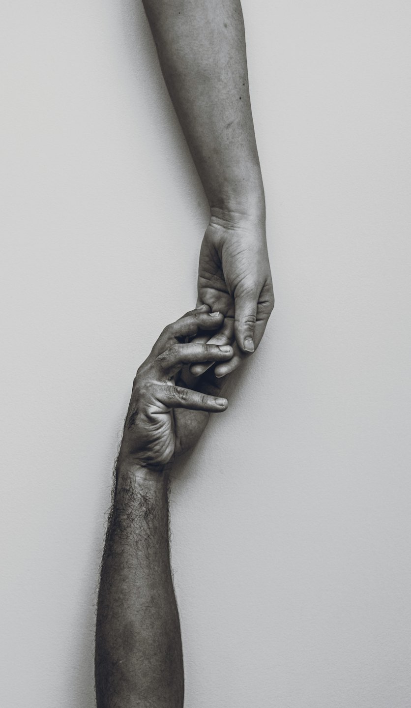 Two hands reaching toward each other and touching fingertips.