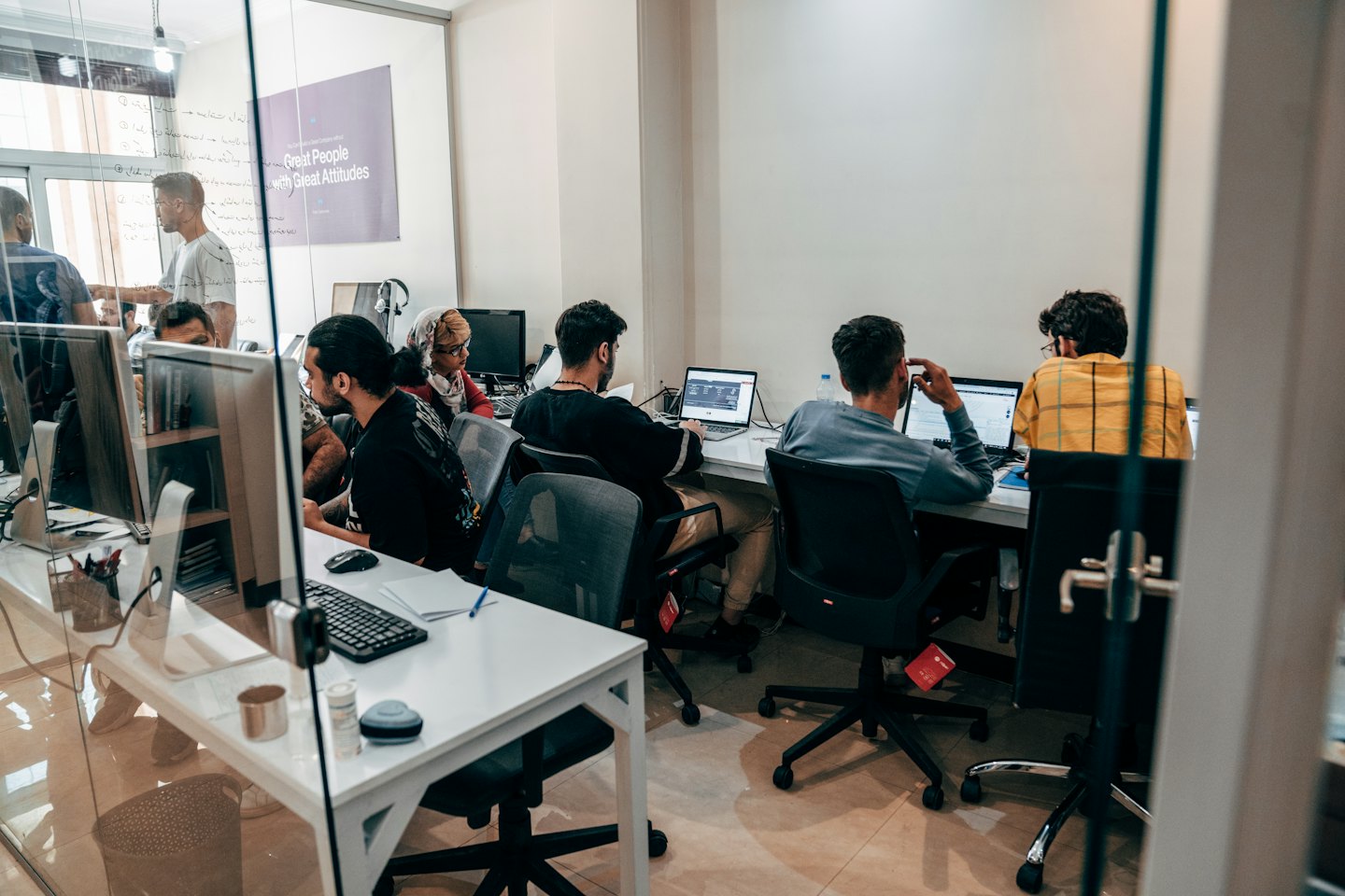 Young adults collaborate on laptops in a modern office.