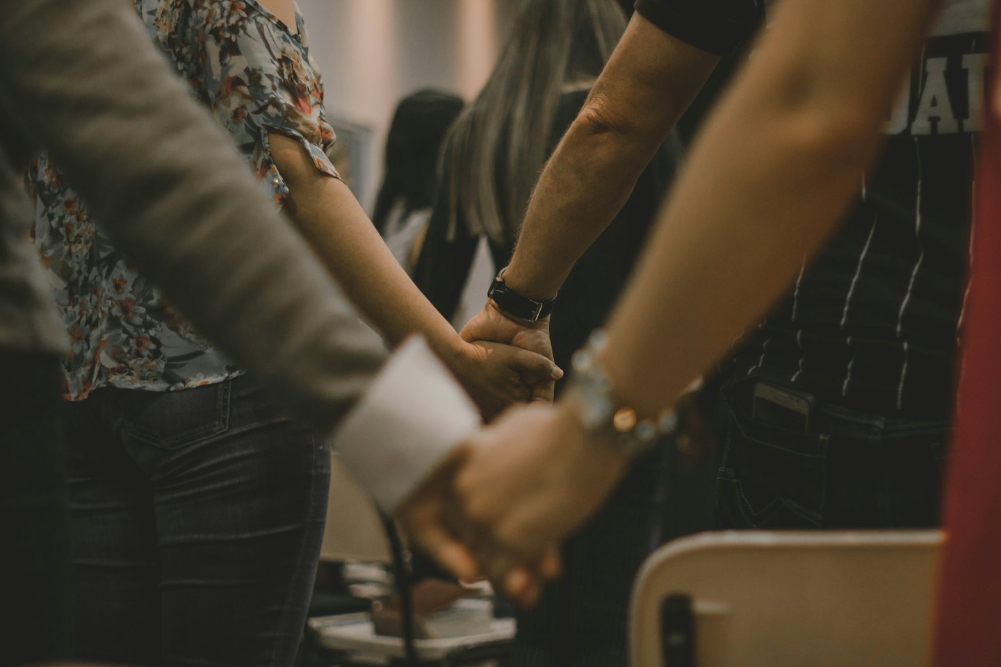 Several diverse people holding hands together in a circle.