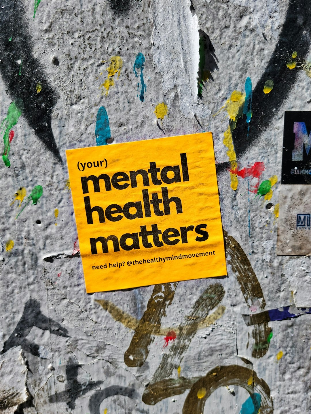 Mental health awareness sticker attached to a graffiti covered wall.