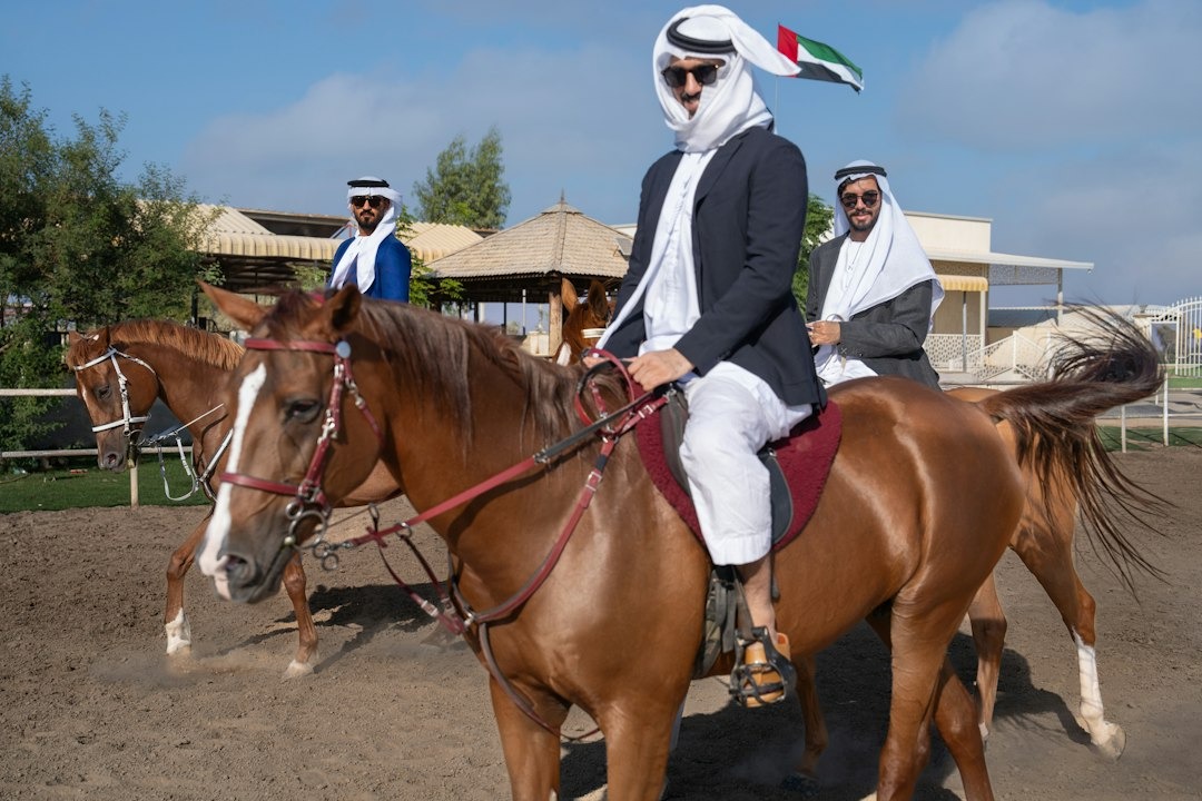Three men on horses ride in an outdoor arena.