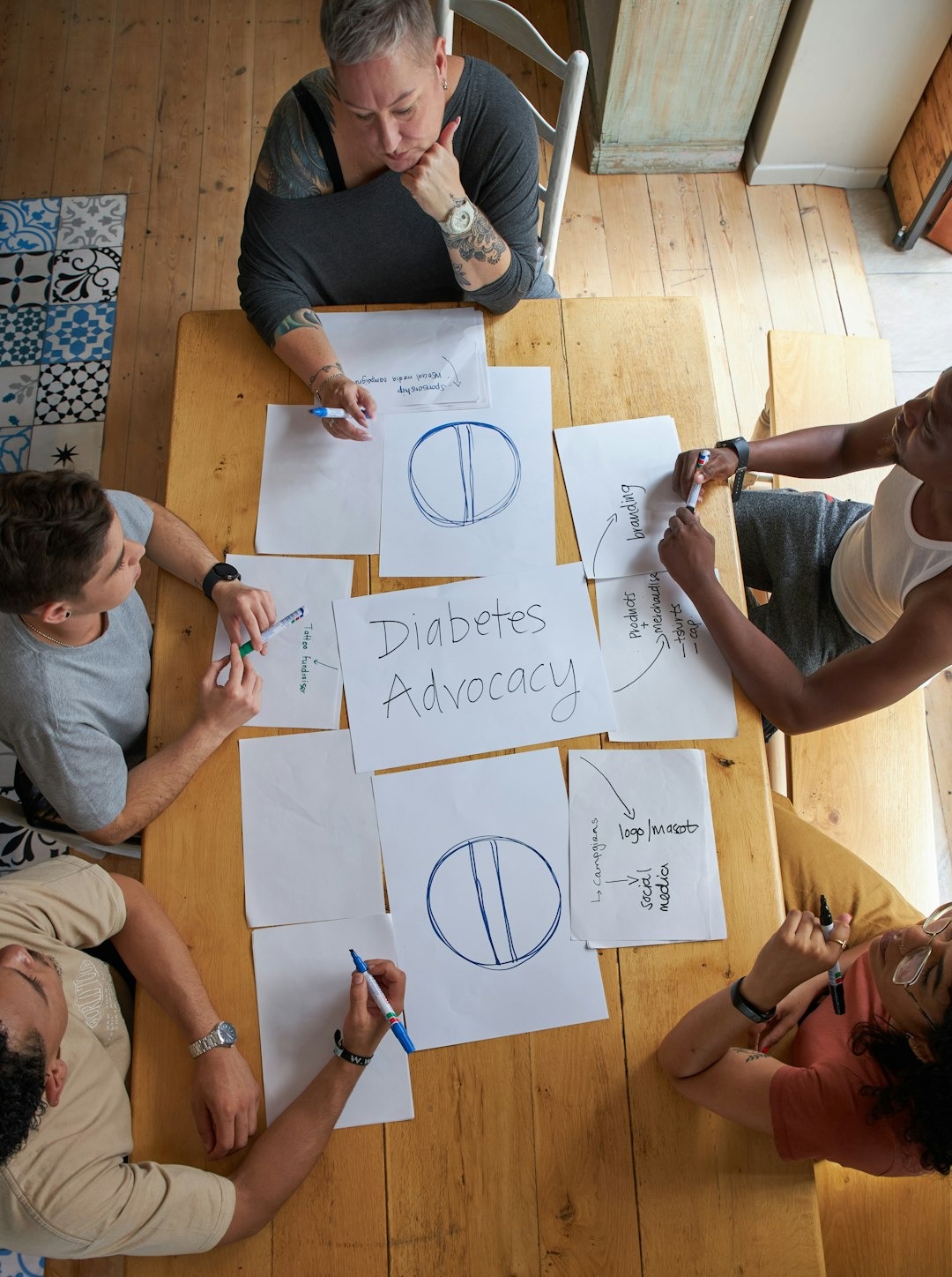 Four diverse people brainstorm diabetes advocacy ideas at a table.